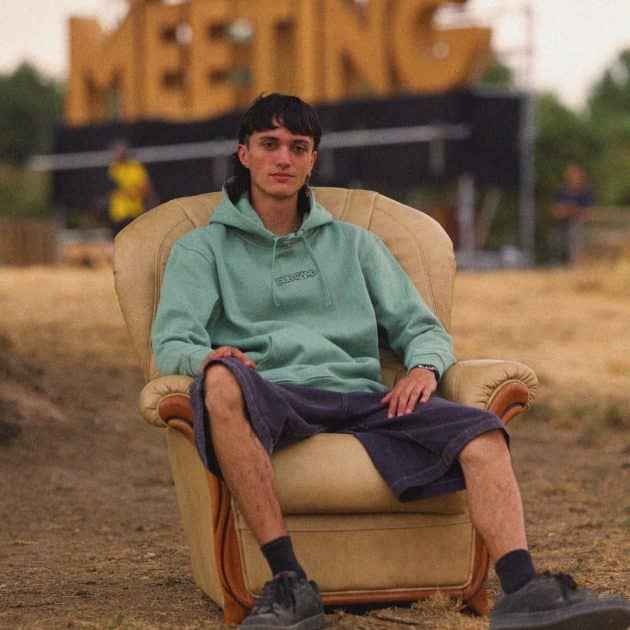 Homme sur un fauteuil crème, portant le sweat-shirt vert mousse du Dub Camp 2026